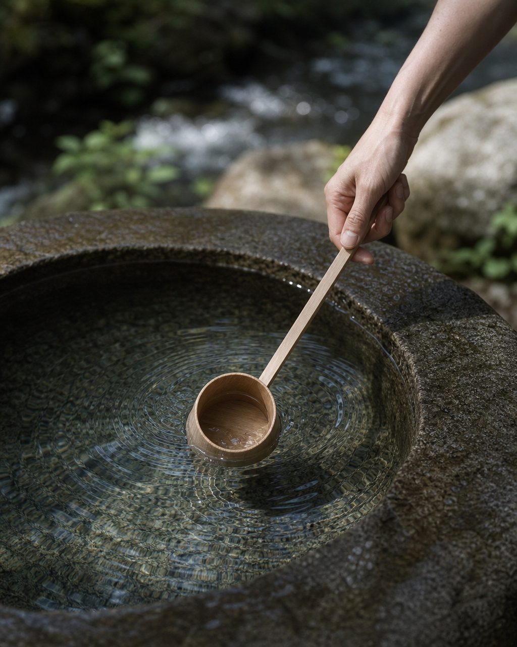 湧き水を柄杓で汲む手元と水面の波紋